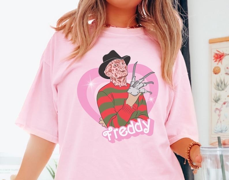 Freddy doll tshirt, horror movie doll tshirt, funny Halloween graphic tee, pink spooky shirt, retro aesthetic, scary...